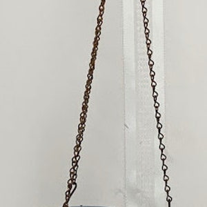 May include: A light blue ceramic hanging planter with a metal chain. The planter is empty and ready to be filled with plants.
