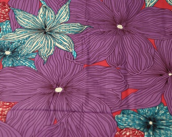 Op de afbeelding: Paarse en blauwe bloemenstof met een herhalend patroon van bloemen. De bloemen zijn zwart omrand en hebben een wit centrum.