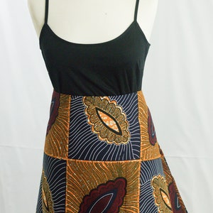 May include: A black tank top with a long, flowing skirt. The skirt is made of a colorful African print fabric with a geometric pattern in shades of orange, brown, and blue.
