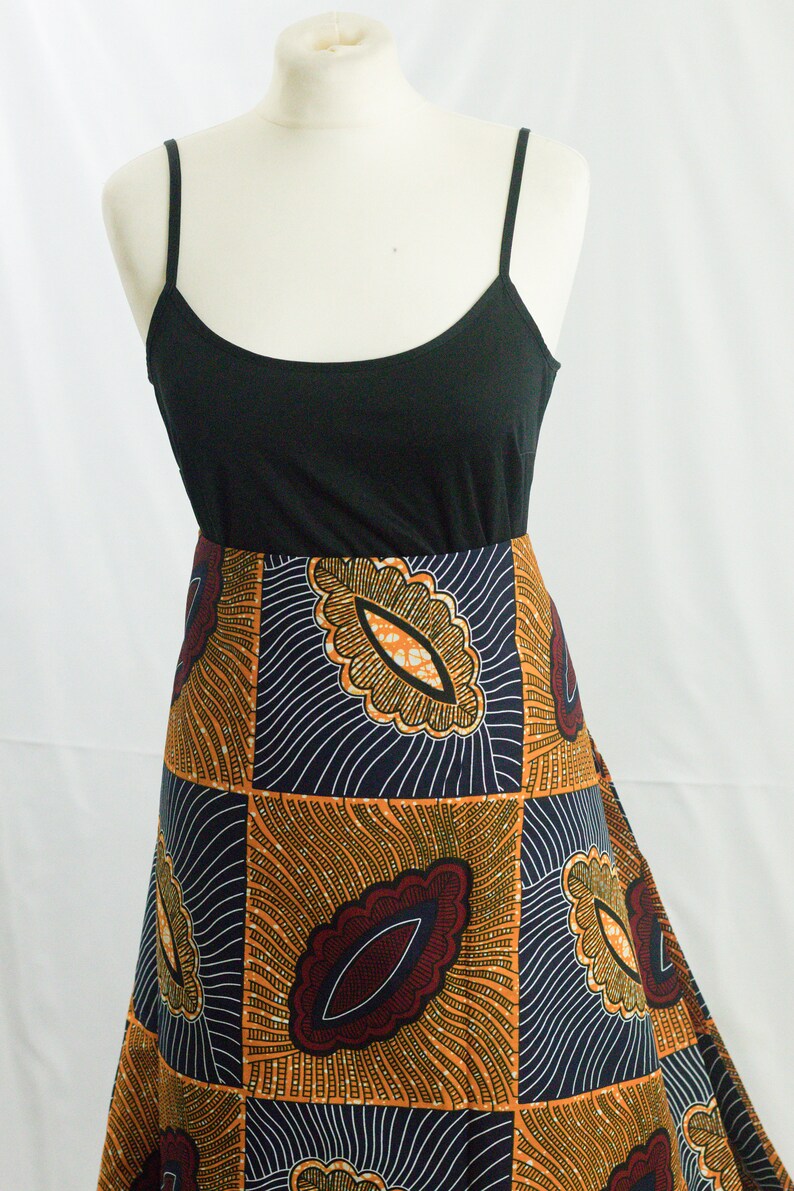 May include: A black tank top with a long, flowing skirt. The skirt is made of a colorful African print fabric with a geometric pattern in shades of orange, brown, and blue.
