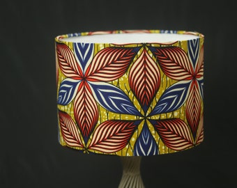 May include: A cylindrical lampshade with a colorful floral pattern. The pattern features red, blue, white, and yellow flowers on a gold background.