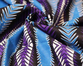 May include: A close-up of a fabric with a geometric pattern. The fabric is blue, purple, white, and black. The pattern is made up of repeating triangles and zigzags.