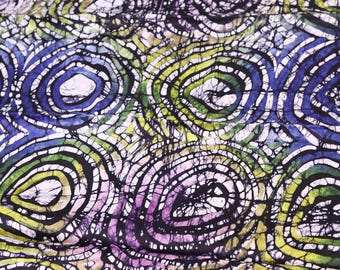 Puede incluir: Una tela colorida con un patrón batik de círculos giratorios en tonos de azul, verde, morado y blanco sobre un fondo negro.