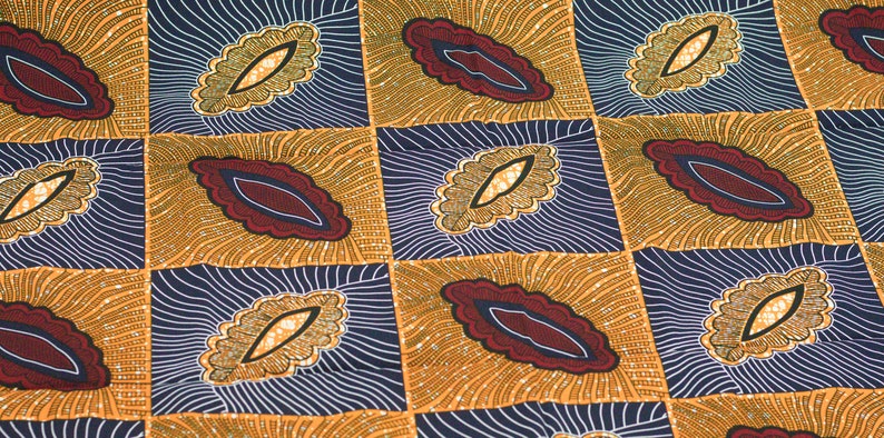 May include: A fabric with a repeating pattern of stylized leaves in shades of gold, brown, red, and blue. The leaves are outlined in black and have a textured appearance.