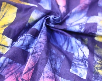 Puede incluir: Tela morada con un patrón repetido de cuadrados azules, amarillos y rosas. La tela tiene un efecto tie-dye y está arrugada.