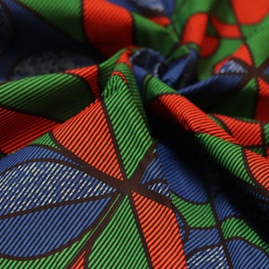 May include: Close-up of a fabric with a geometric pattern in shades of blue, green, and red. The fabric is folded and has a textured surface.
