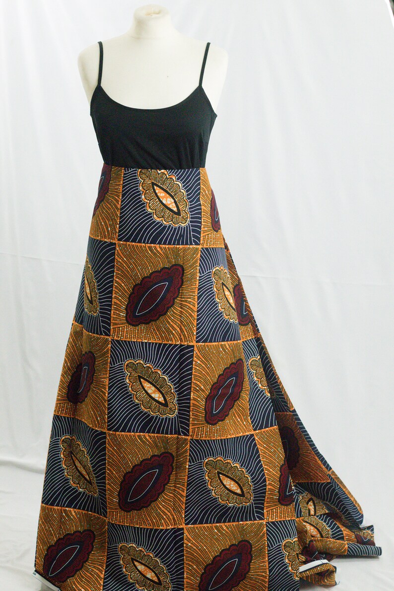 May include: A long, flowing skirt with a geometric pattern in shades of orange, brown, and blue. The skirt is made of a patterned fabric with a repeating design of stylized leaves.