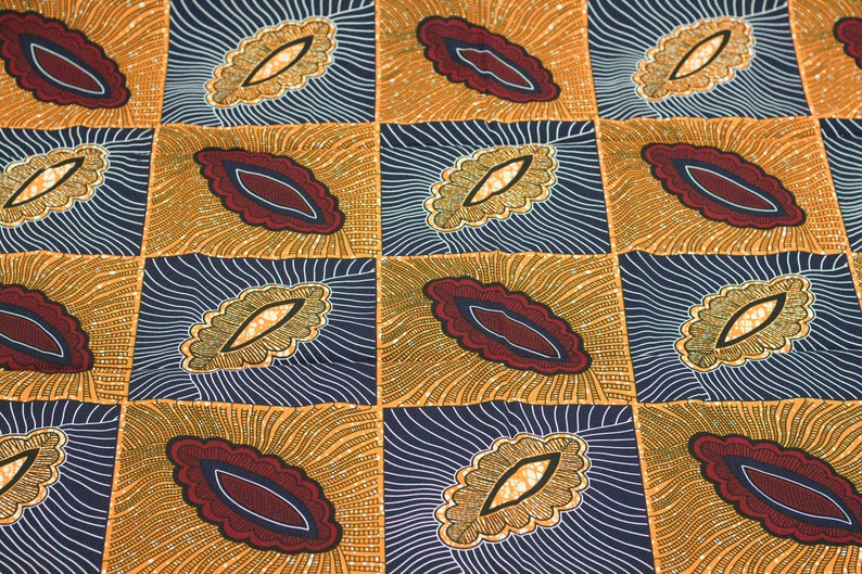 May include: A fabric with a repeating pattern of stylized leaves in shades of gold, brown, red, and blue. The leaves are outlined in white and have a textured appearance.