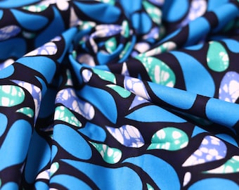 May include: Blue and black fabric with a white and green abstract pattern. The fabric is folded and textured.