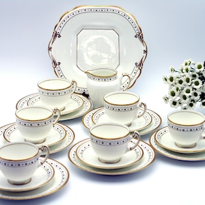 Puede incluir: Un juego de té vintage con tazas, platillos y una jarra de leche de porcelana blanca. Cada pieza está adornada con un borde dorado y un borde azul y dorado con puntos. También se incluye una fuente grande con un diseño a juego.