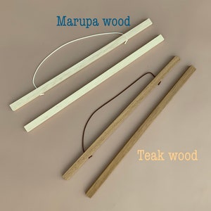 May include: Two sets of wooden poster hangers. The top set is labeled Marupa wood and features light-colored wood with a white cord. The bottom set is labeled Teak wood and features medium-brown wood with a dark brown cord.