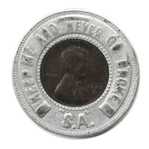 May include: A silver-colored coin with the text "WE ARE AND NEVER GO BROKE" around the edge. The center features a copper penny with the profile of a man. The letters "S.A." are at the bottom.