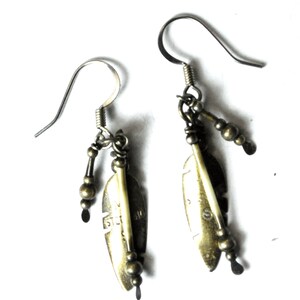 May include: A pair of silver dangle earrings with feather charms and small beads. The feathers are made of metal and have a gold finish.