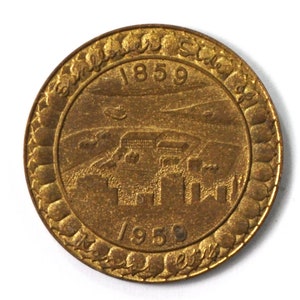 May include: A gold-colored metal token with the words "Salt Lake City" and the years "1859" and "1959" around the edge. The center of the token features a depiction of a city skyline.