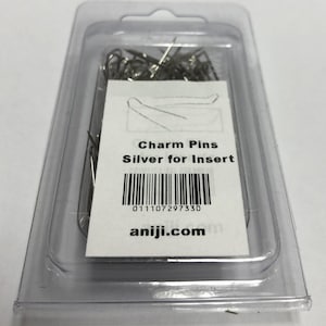 Könnte beinhalten: Eine transparente Plastikverpackung mit silbernen Charmstiften zum Schmuckbasteln. Die Verpackung hat ein weißes Etikett mit dem Text "Charm Pins Silver for Insert" und einem Barcode mit der Nummer "011107297330". Das Etikett enthält auch die Website "aniji.com".