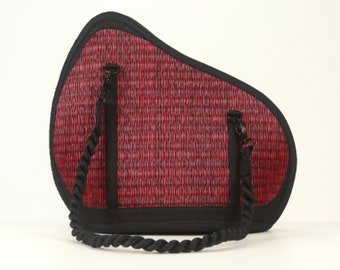 May include: A red and black woven bag with a black rope handle. The bag has a unique curved shape.