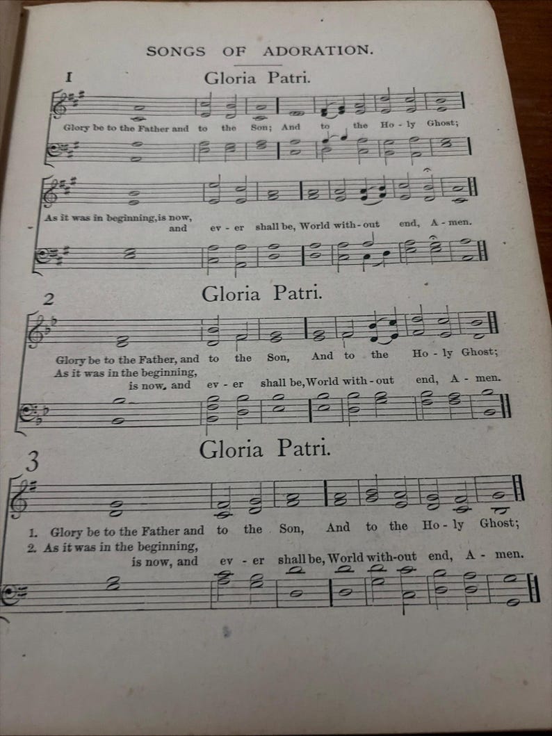 May include: A vintage sheet music page titled "Songs of Adoration" featuring musical notation and the text "Gloria Patri." The page is aged with visible wear and tear, and the text is in English.
