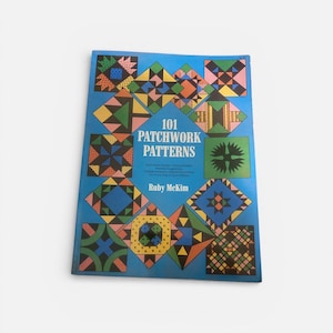 May include: A book titled "101 Patchwork Patterns" by Ruby McKim. The cover is blue and features colorful patchwork designs in various geometric shapes. The patterns include squares, diamonds, and triangles in shades of green, orange, blue, and pink.