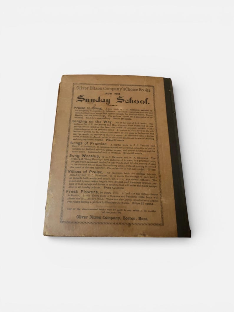 May include: An antique book titled "Sunday School" with a worn, tan cover and black spine. The cover features text including "Oliver Ditson Company" and book titles like "Praise in Song" and "Singing on the Way."