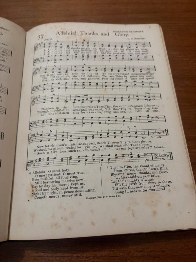 May include: Open book displaying sheet music with the title "Alleluia! Thanks and Glory." The page features musical notation, lyrics, and the number 37 at the top. The text includes phrases like "Children in the" and "Jesus Christ, the children's King."
