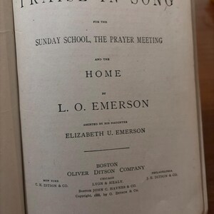 May include: Open book with the title "PRAISE IN SONG" at the top. The text below reads "FOR THE SUNDAY SCHOOL, THE PRAYER MEETING AND THE HOME". The book is by L. O. EMERSON, assisted by his daughter, ELIZABETH U. EMERSON. Published by OLIVER DITSON COMPANY.