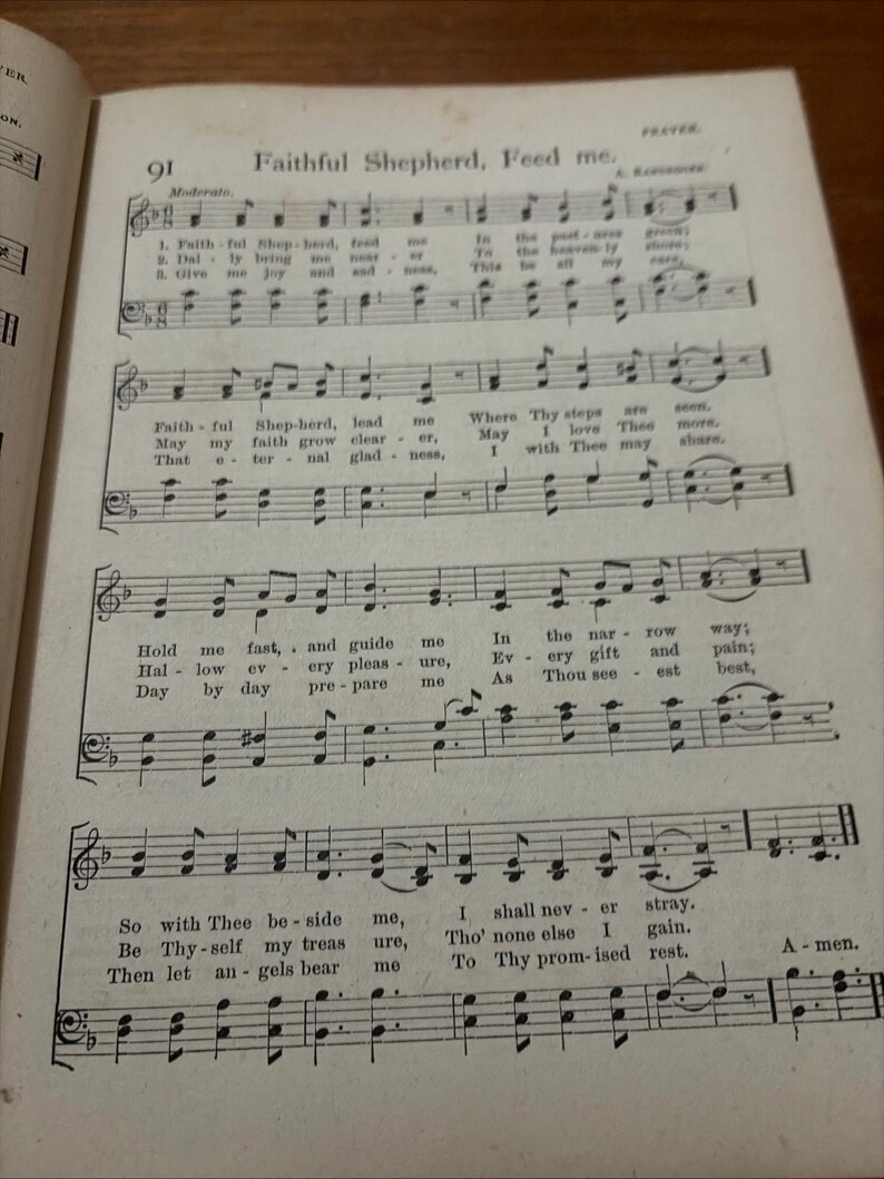 May include: Open book page with sheet music and the title "Faithful Shepherd, Feed me." The page is aged with visible musical notes and lyrics. The text includes phrases like "Hold me fast" and "I shall never stray."