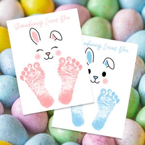May include: Two printable cards with bunny illustrations and the text "Somebunny Loves You". The cards are designed for baby footprints, one with pink footprints and the other with blue footprints.