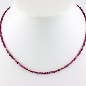 Könnte beinhalten: Eine zarte Halskette aus kleinen, runden, tiefrosa Perlen mit goldenen Akzenten.