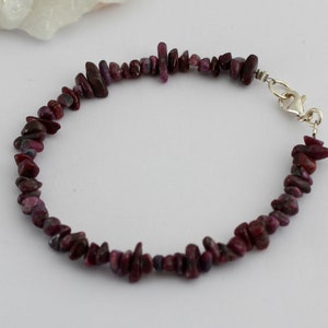 May include: A delicate bracelet made with small, irregular pieces of ruby. The bracelet is secured with a silver clasp.