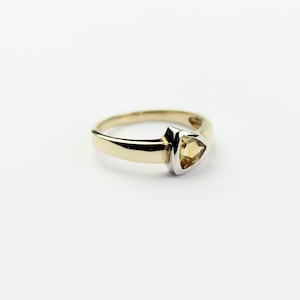 May include: A gold ring with a triangular shaped topaz gemstone set in a white gold setting.