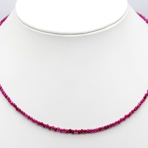 May include: A delicate necklace made of small, faceted ruby beads. The necklace is strung on a silver chain and is approximately 18 inches long.