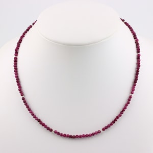 Peut inclure: Un collier composé de petites perles rondes rose foncé avec des accents argentés.