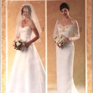 May include: Butterick sewing pattern B6803 for bridal gowns in size A5 (6-8-10-12-14). The envelope features two white wedding dresses: one strapless with a veil and one with long sleeves and gold embroidery, both shown with floral bouquets.