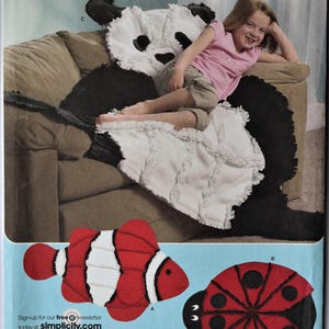 May include: Simplicity fleece throws pattern featuring a panda bear, a clownfish, and a ladybug. The panda bear is black and white, the clownfish is red and white, and the ladybug is red with black spots. The pattern is designed by Robin Greenwood.