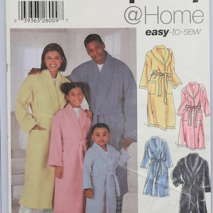May include: A Simplicity 5931 sewing pattern envelope for robes in sizes XS-L and XS-XL. The cover features illustrations and photographs of individuals wearing long-sleeved, belted robes in yellow, pink, and blue, with easy-to-sew instructions.