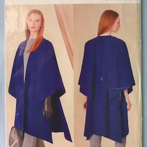 May include: Vogue Patterns R11117 sewing pattern envelope featuring a design by Tom and Linda Platt. The image displays a deep blue cape shown from both front and back views, worn over a grey top and trousers. The pattern includes sizes XS to XXL.