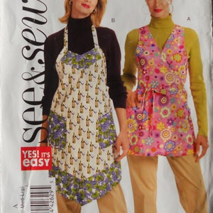 May include: Two aprons are shown. One is white with a wine bottle pattern and purple grape clusters. The other is pink with a floral pattern. The aprons are part of a sewing pattern.