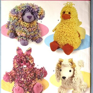 May include: A Simplicity sewing pattern envelope 3933 featuring four plush animal designs: a multi-colored shaggy dog, a yellow duck, a pink shaggy rabbit with white teeth, and a white poodle with gold bows. The pattern is labeled One Size.