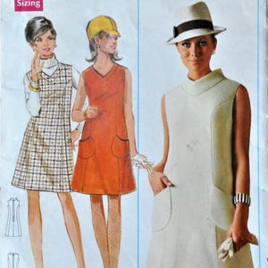 May include: A Butterick 4790 sewing pattern envelope featuring illustrations of three sleeveless dresses. View A is a solid light-colored dress with pockets, View B is an orange dress with pockets, and View C is a plaid dress worn over a turtleneck.