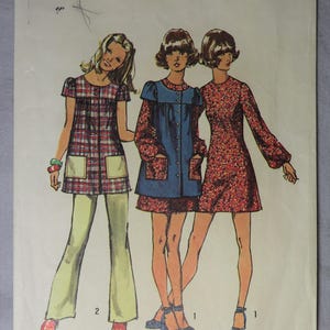 May include: Vintage Simplicity sewing pattern featuring three illustrated figures in 1970s-style outfits. The pattern includes a plaid tunic with pockets, a blue tunic dress, and a floral print dress. The pattern number is 9834.
