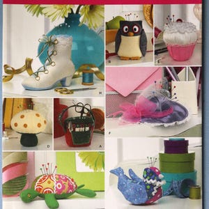 May include: Simplicity sewing pattern 2990 for various pincushions including a boot, owl, cupcake, mushroom, small bag, hat, turtle, and bird. The pattern features designs by Andrea Schewe and includes a barcode and text on the front cover.
