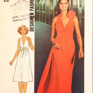 May include: A Simplicity 7712 sewing pattern envelope for a floor-length dress with a deep V-neckline, a waist tie, and a large fabric flower accent on the shoulder. The package features the text Designer Fashion, size Small 8-10, and 1.75.