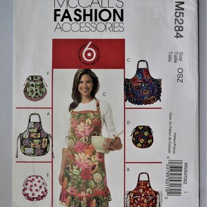 May include: McCall's Fashion Accessories sewing pattern. The package features a woman wearing a floral apron, with examples of other apron designs. The package includes the text "6 Great Looks, One Easy Pattern".