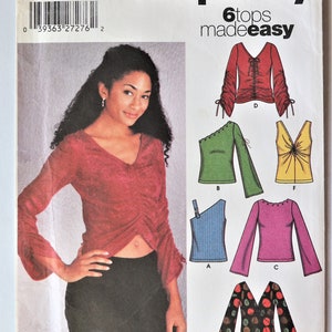 May include: Simplicity sewing pattern for six tops. The pattern features various top designs, including a red ruched top, a one-shoulder top, and a V-neck top. The pattern size is P5, sizes 12-20.