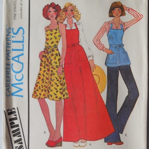 May include: Vintage McCall's sewing pattern envelope featuring illustrations of women's aprons and dresses. The designs include a yellow floral dress, a long red apron, and a blue apron with jeans. The text reads "MISSES' BUTCHER APRON".