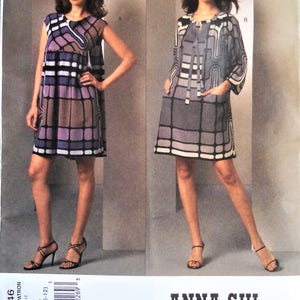 May include: A pattern for two dresses with geometric designs. One dress is sleeveless, the other has sleeves. The dresses are in shades of purple, gray, and white. The pattern is labeled "V1046" and features the "ANNA SUI" logo.
