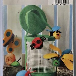 May include: A sewing pattern for soft toy insects, including a ladybug, bee, butterfly, and snail. The pattern features a green felt basket with a handle. The text "Butterick" and "SOFT STUFF" are visible.