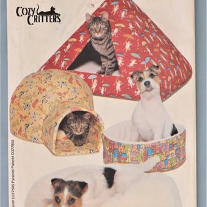 May include: A pattern for Cozy Critters pet beds. The image shows a cat in a red tent-shaped bed, a dog in a round bed, and a cat in a yellow igloo-shaped bed. The pattern includes all sizes.
