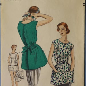 May include: Vintage Vogue pattern envelope featuring illustrations of women's tops and dresses. The cover displays the text "VOGUE PATTERN" and "MEDIUM (36-38)". The copyright date is 1953.