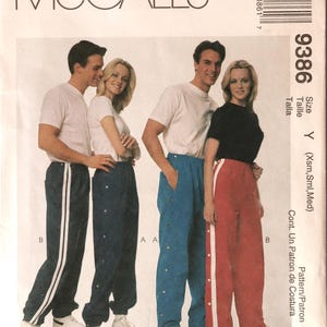 May include: A McCall's 9386 sewing pattern envelope for break away pants. The cover features illustrations of four individuals wearing various styles of athletic pants with side snap closures and side stripes in navy, blue, and red colors.